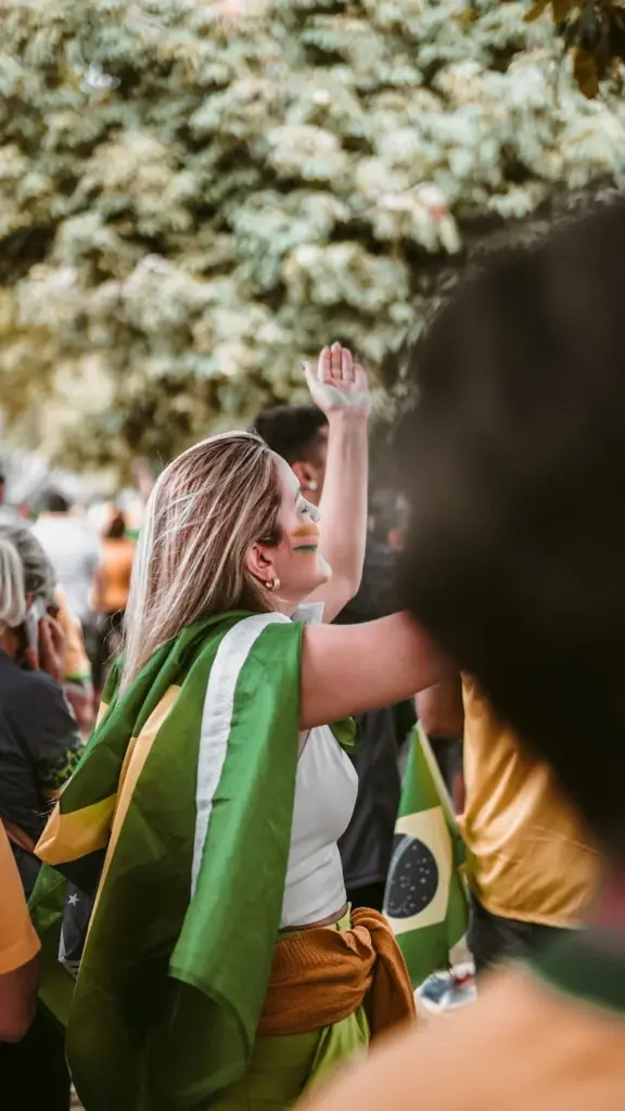 A lively street celebration with people waving Brazilian flags joyously outdoors.