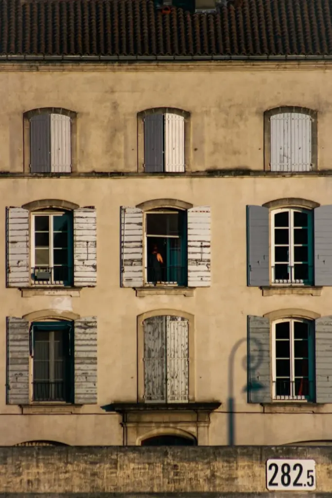 A picturesque building in Arles, France featuring classic wooden shutters and charming European architecture.