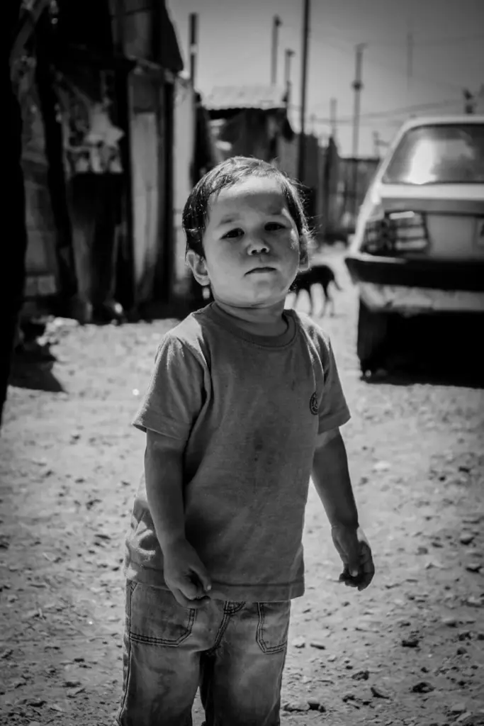 A young boy stands outdoors in a monochrome setting, highlighting childhood innocence.