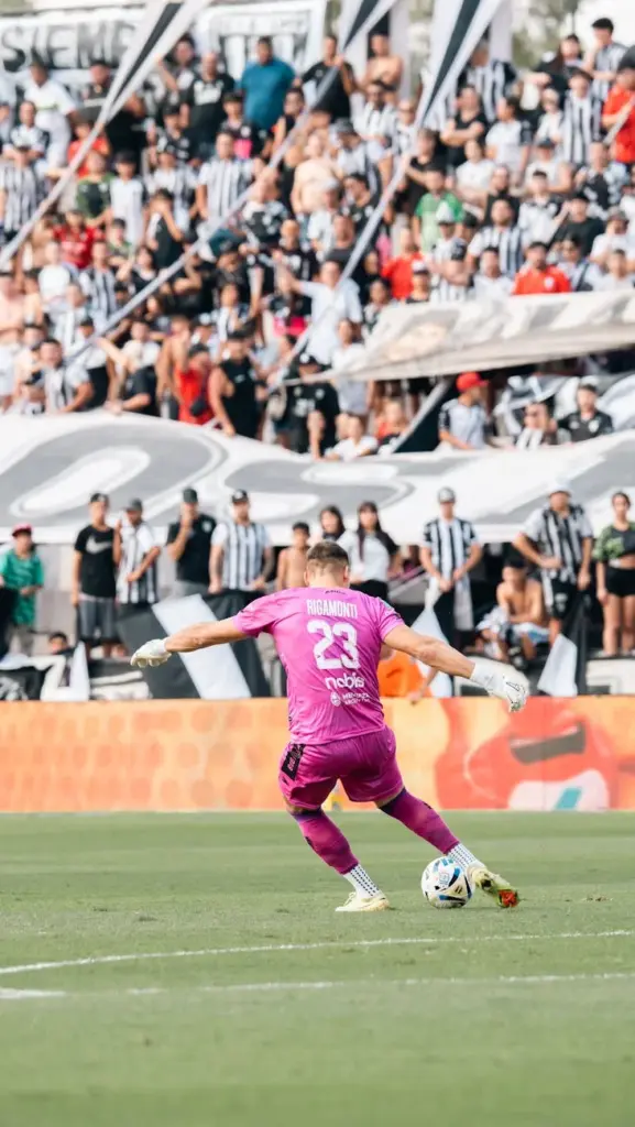 Goalkeeper in action during a soccer match with fans in the stadium.