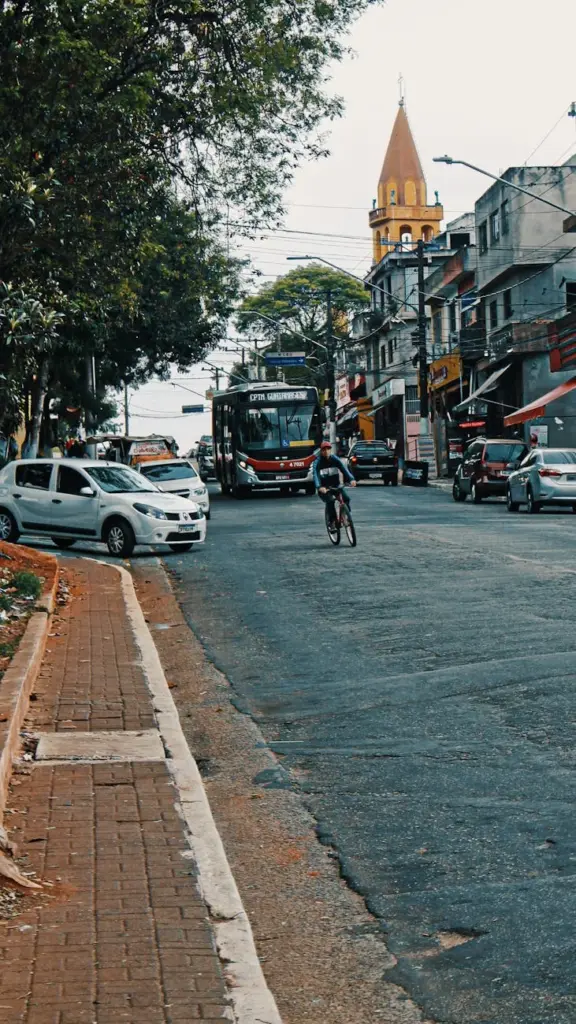 Busy city street featuring a cyclist navigating through traffic with parked and moving vehicles.