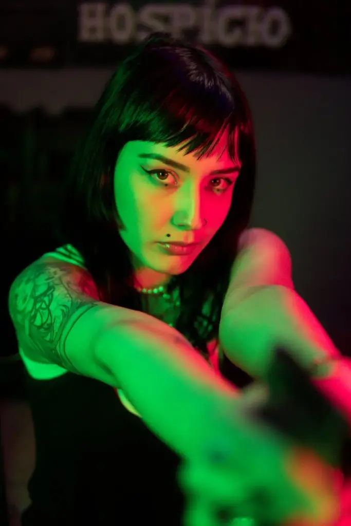Portrait of a tattooed woman with striking colored lights, creating an edgy and artistic vibe.