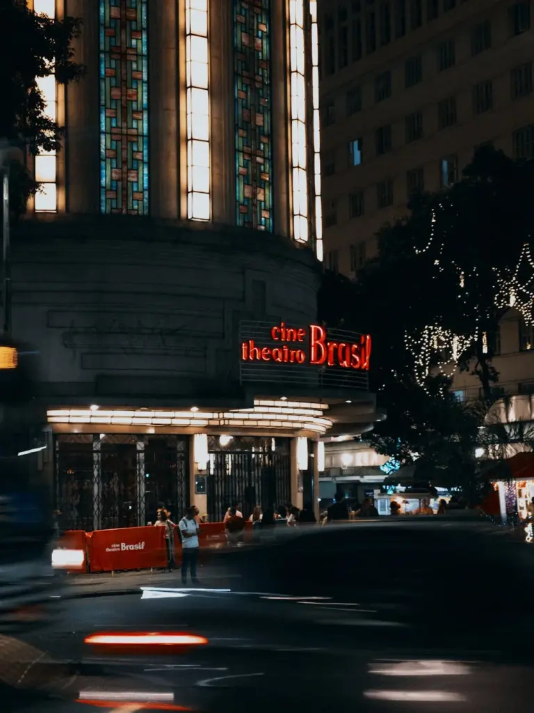 Night scene of Cine Theatro Brasil in Belo Horizonte with city lights and bustling streets.