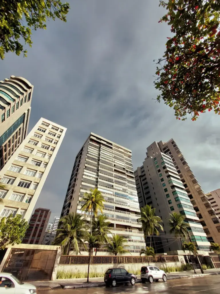 Stunning low angle view of modern skyscrapers against a cloudy sky with palm trees in Recife, Brazil.