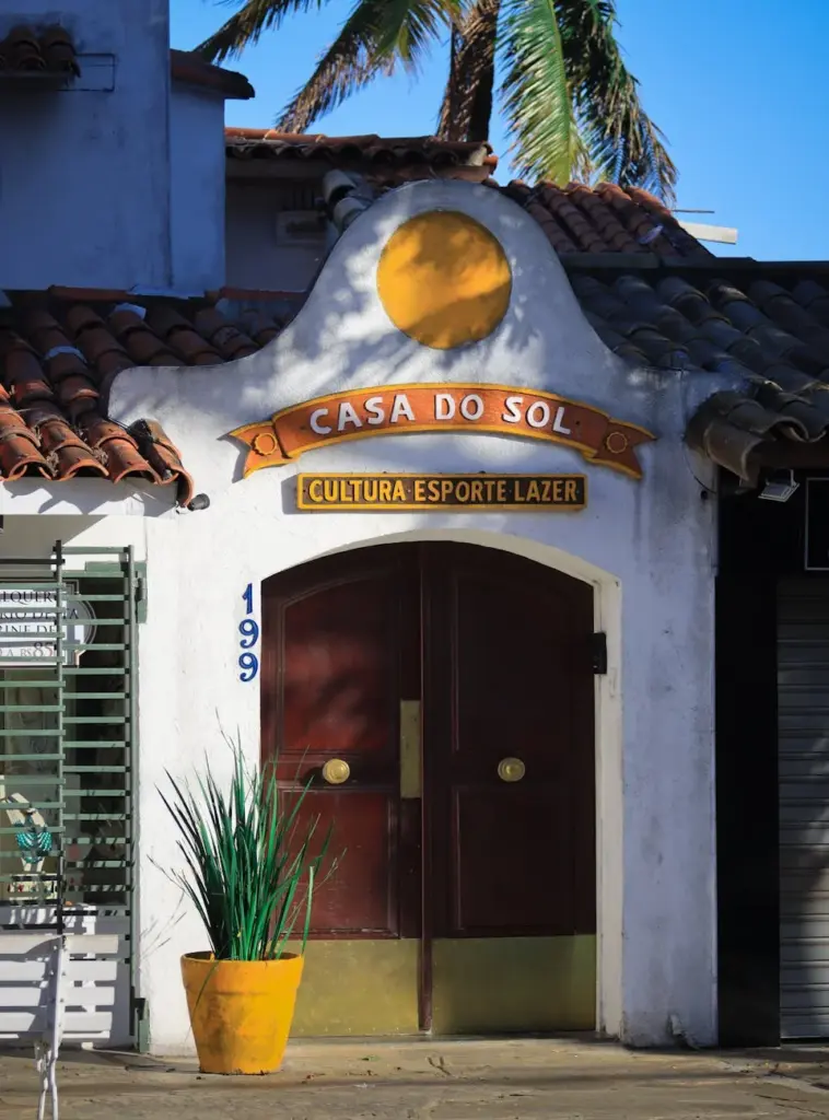 Colorful entrance of Casa do Sol with palm trees, vibrant design, and cultural signage.