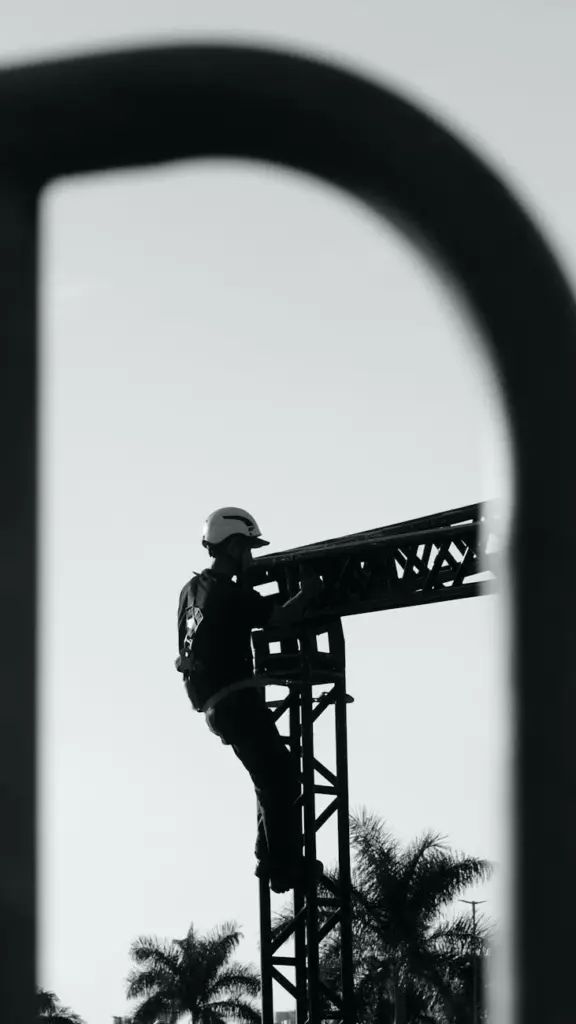 Monochrome image of a construction worker climbing scaffolding, framed artfully.