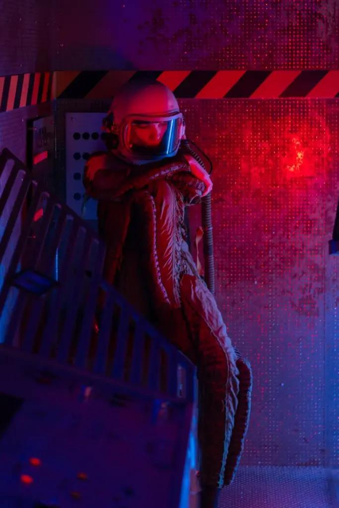 A spacewoman in a spacesuit navigates a sci-fi spaceship with blue and red lighting.
