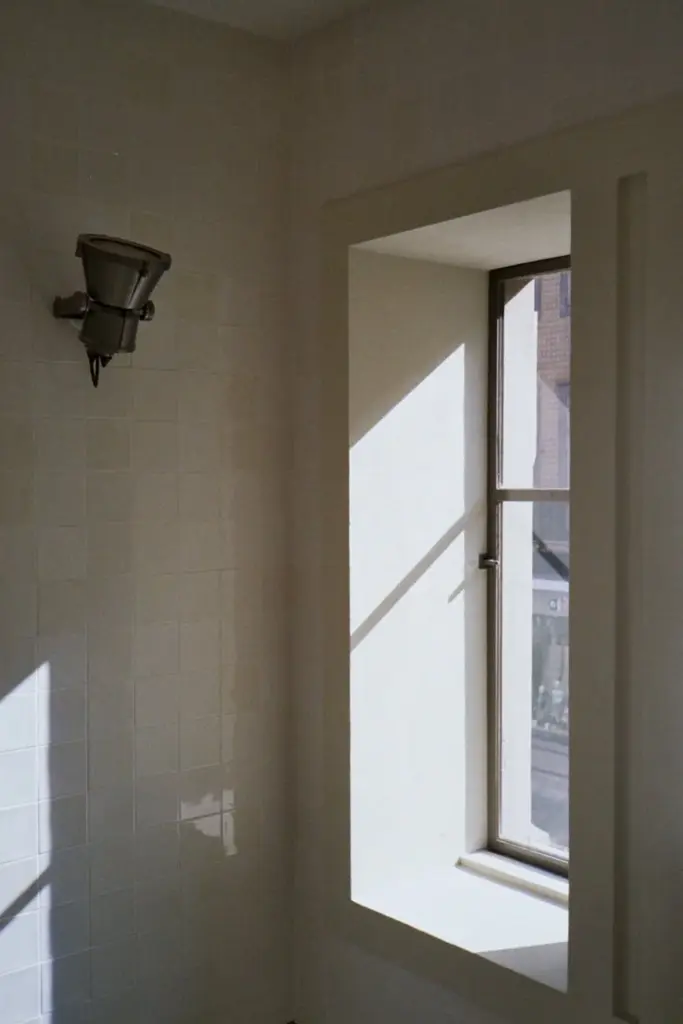 A minimalist interior with natural light and shadow play through a window in Porto, Portugal.