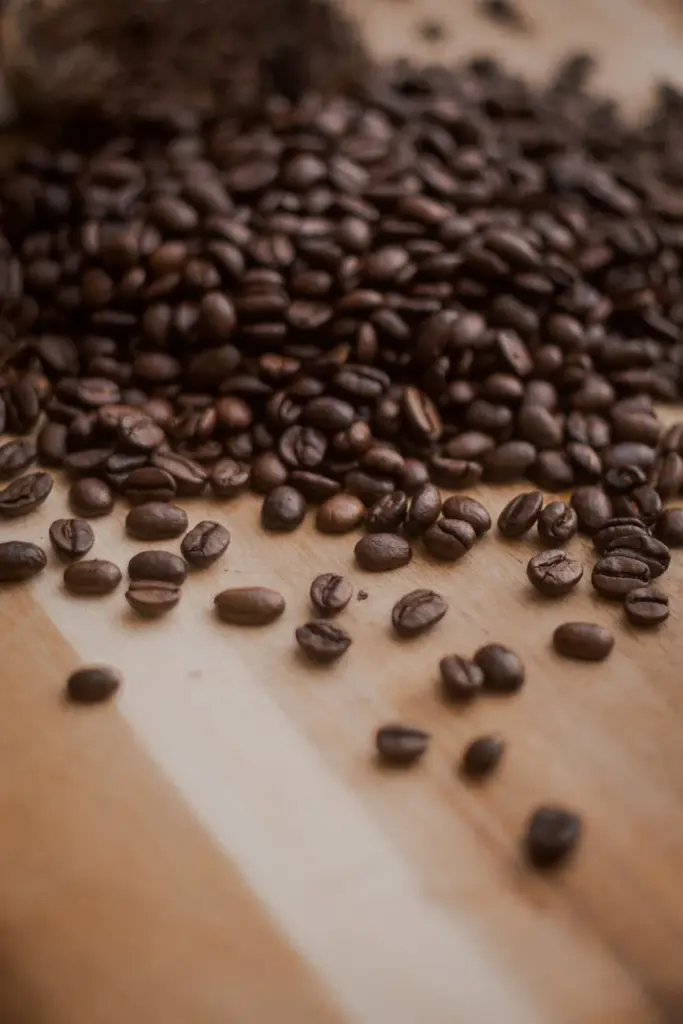A detailed view of roasted coffee beans scattered on a wooden surface, perfect for coffee-related content.