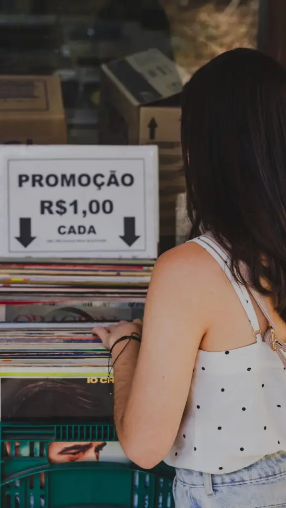 Back view of a woman browsing discounted vinyl records in Brasília market.
