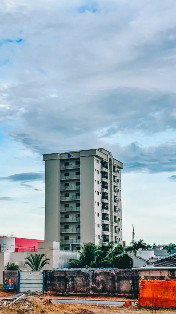 A tall apartment building stands prominently against a backdrop of dramatic clouds.