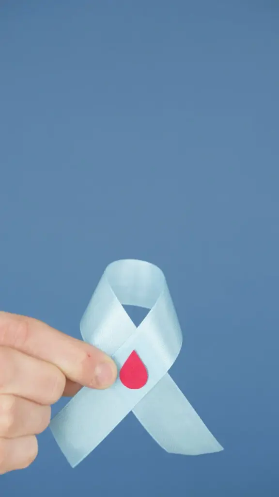 Blue awareness ribbon with a red blood drop symbolizing diabetes support and health.
