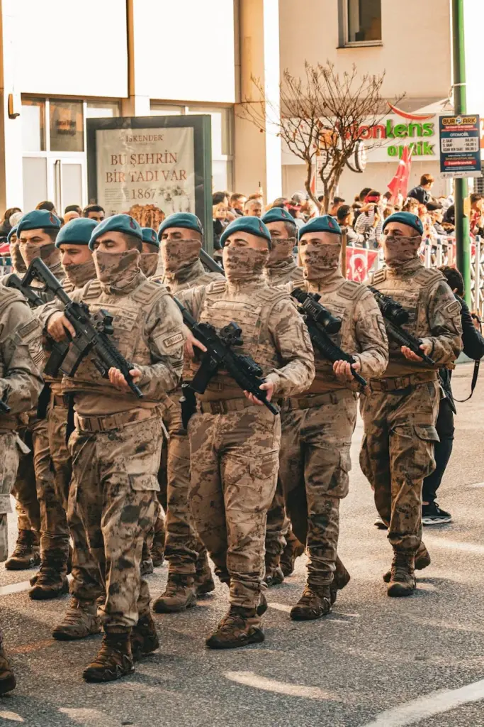Group of soldiers marching in a parade with spectators. Urban setting.
