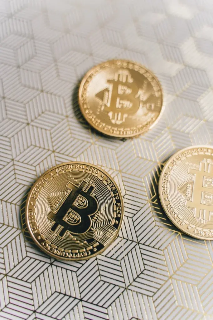 Close-up of gold Bitcoin coins on a geometric patterned surface.