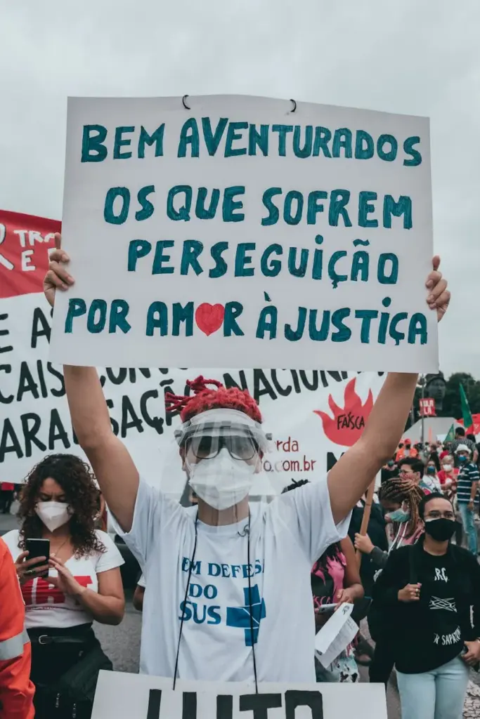 A protester wearing a face mask holds a sign advocating for justice in a Brazilian demonstration.
