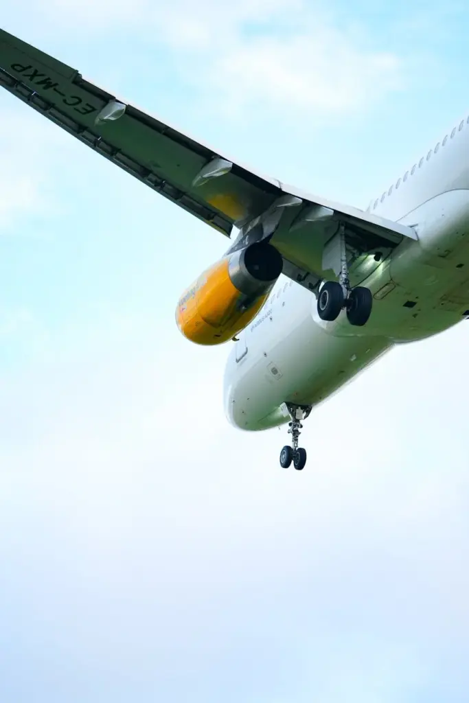 A low-angle view of an airplane mid-flight, showcasing the landing gear against a clear blue sky.