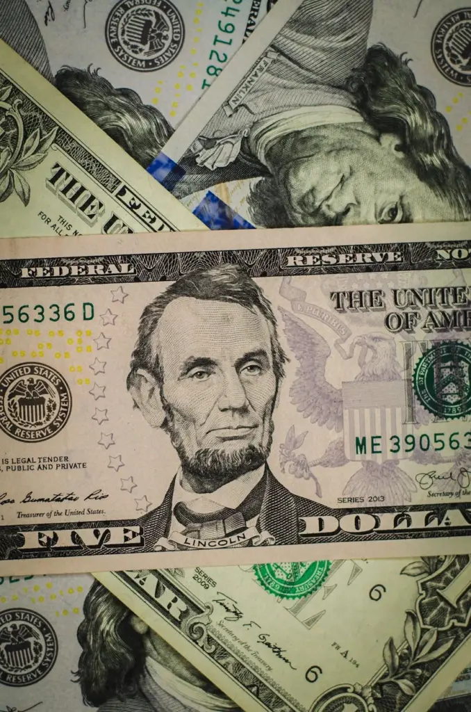Pile of various US dollar banknotes featuring Abraham Lincoln and Benjamin Franklin.