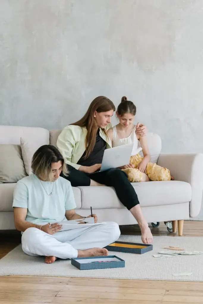 Family enjoying a relaxing day with a laptop and puzzles in a modern living room.