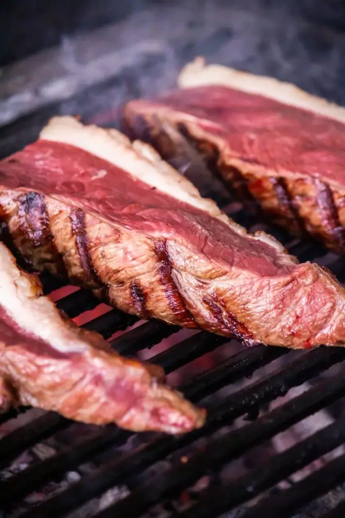 Close-up of tender steaks sizzling on a barbecue grill with rich grill marks.