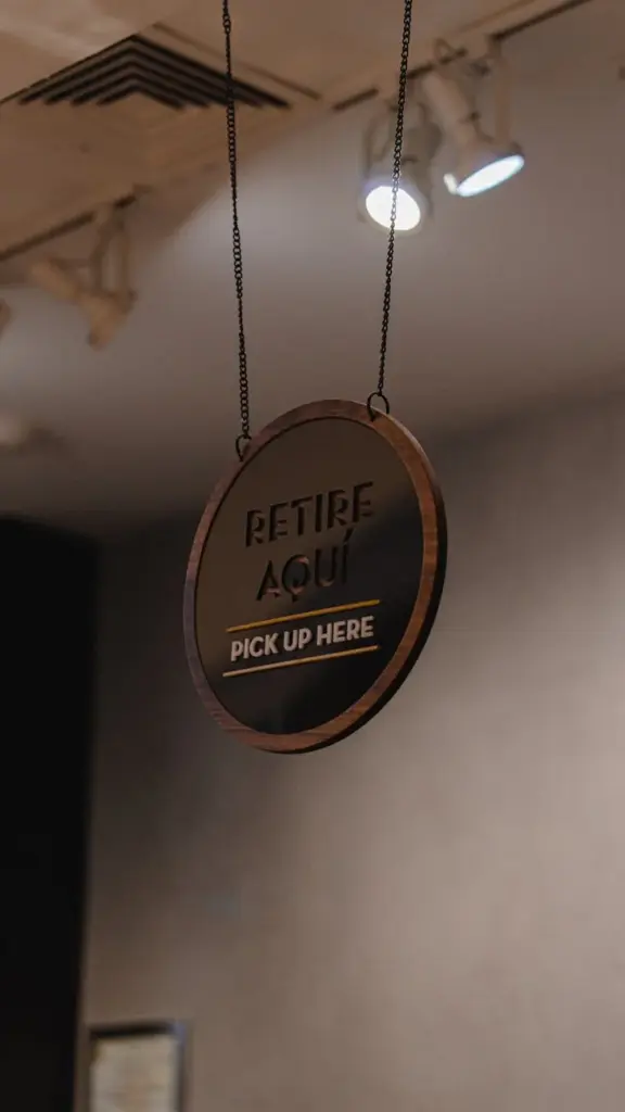 A minimalist hanging sign indicating order pickup in a store setting.