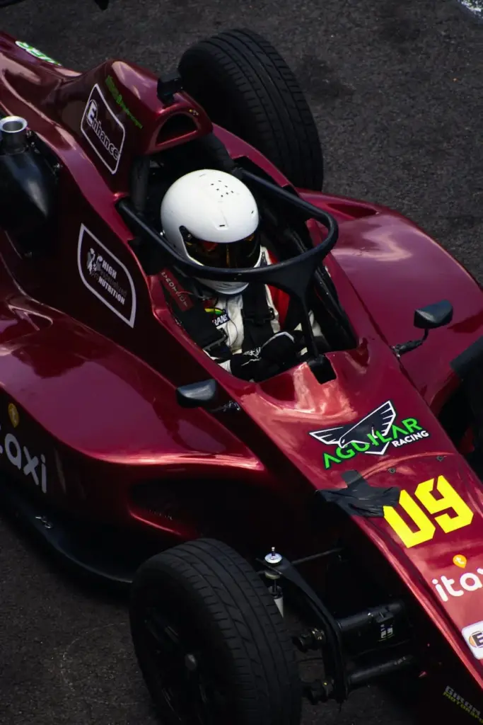 Aerial view of a formula racing driver in a red car on the track, showcasing speed and competition.