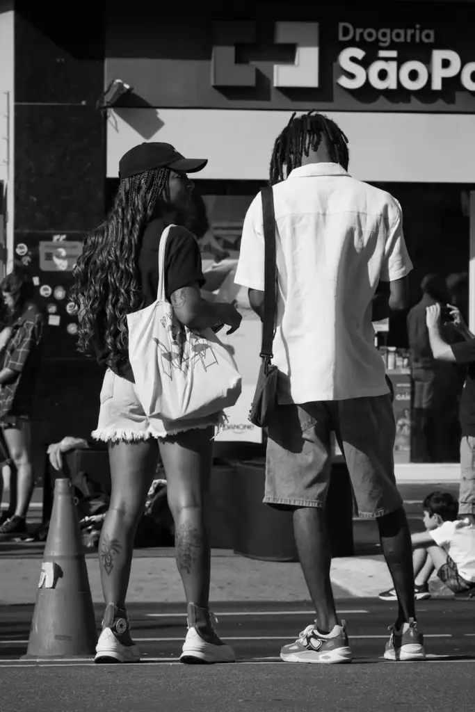 Black and white photo of two people in conversation on a busy São Paulo street.