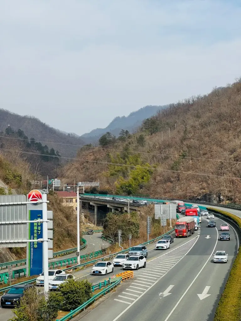 Scenic view of cars on a highway surrounded by mountains in China on a clear day.