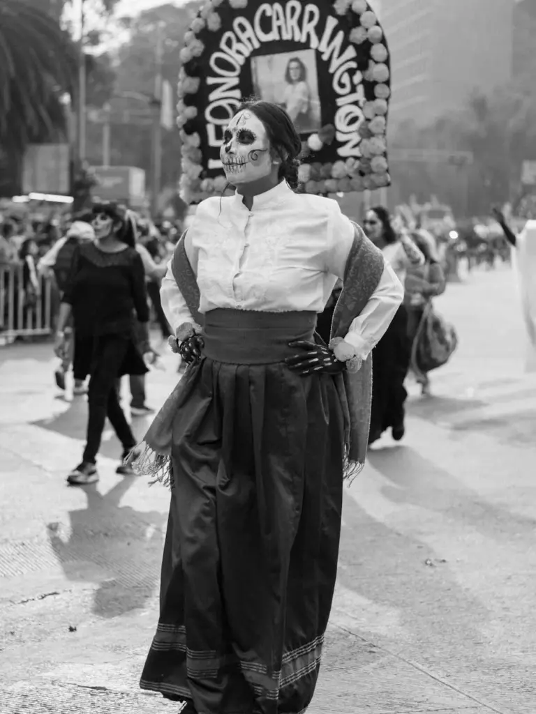 Costumed participant at Day of the Dead celebration with traditional face paint in Mexico City.