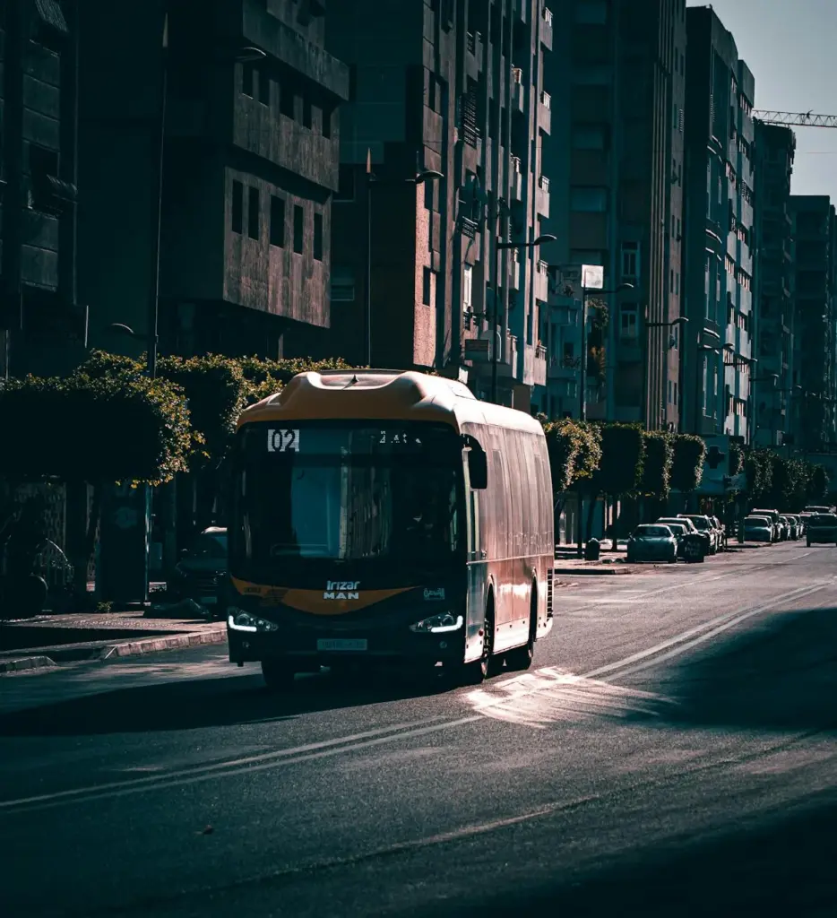 Dramatic image of a modern bus driving along a city street at sunset, highlighting urban transport.