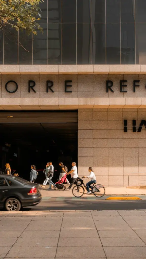 Busy urban scene featuring pedestrians and cyclists outside a modern building facade.