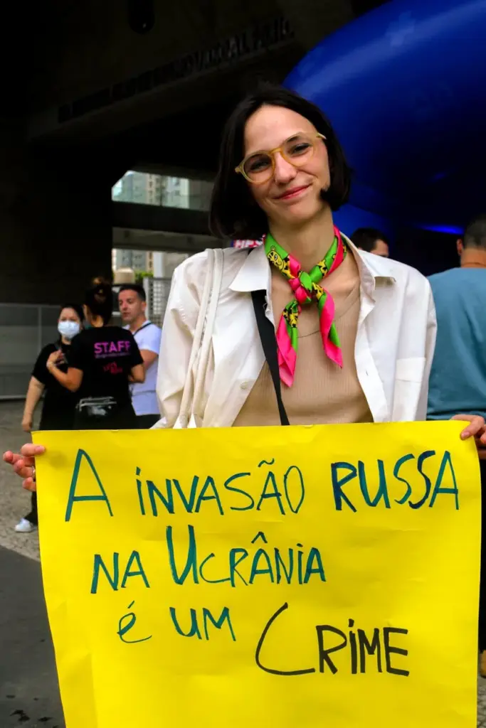 Woman holding anti-war protest sign with a message about Russian invasion in Ukraine.