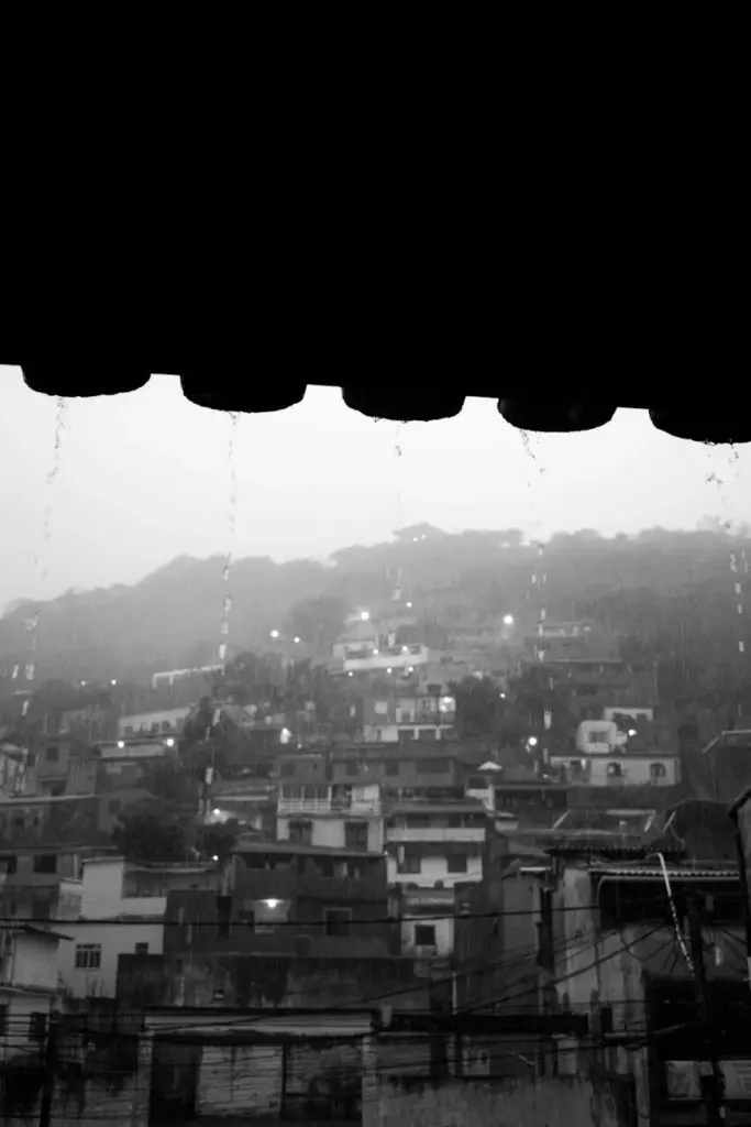 Dramatic black and white photo of favela rooftops in rainy Rio de Janeiro.