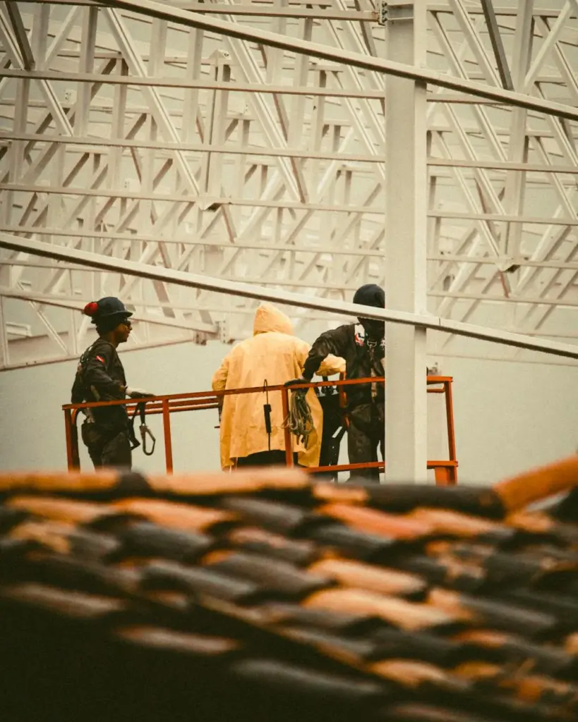 Three workers operating a hoist on a rooftop, emphasizing teamwork and safety in construction.