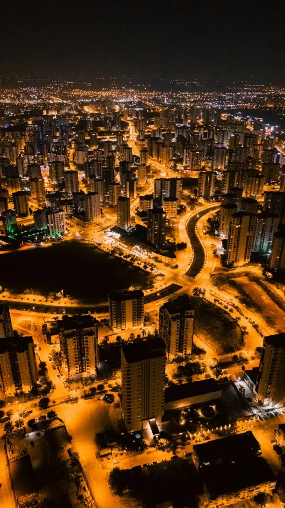 Aerial night view of a vibrant cityscape, illuminated streets and skyscrapers.