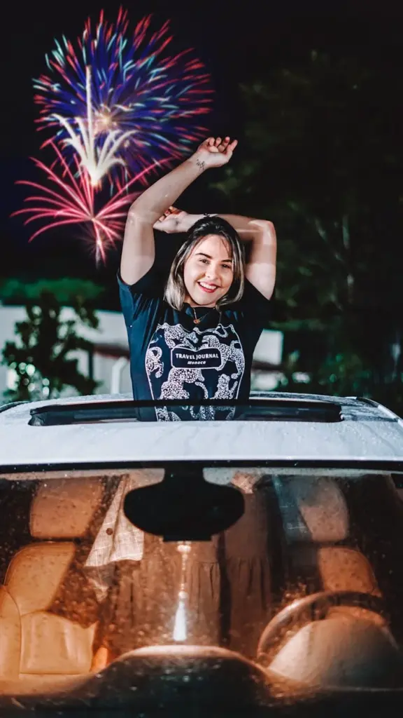 A joyful woman celebrates under a vibrant fireworks display at night.
