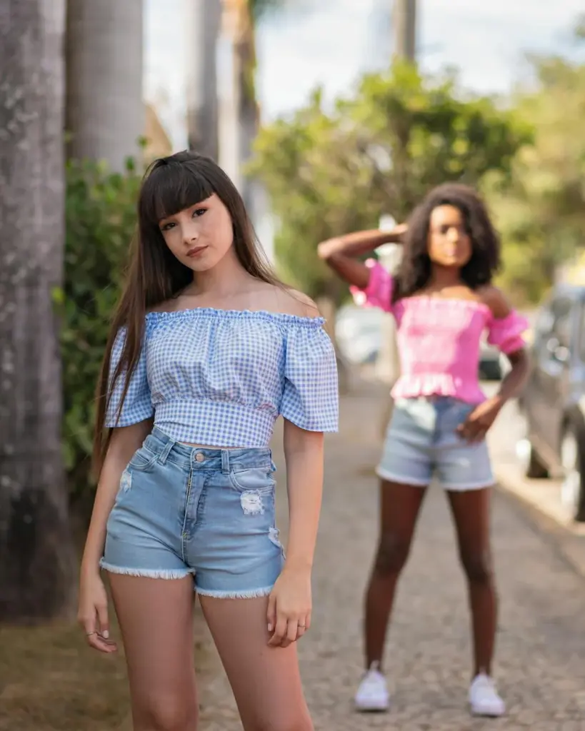 Fashionable teenage girls posing confidently outdoors on a sunny urban sidewalk.