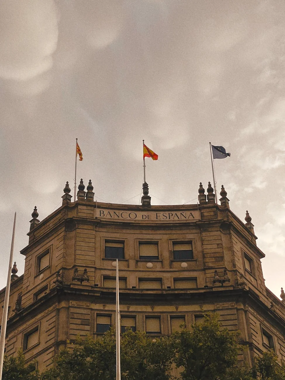 Captivating view of the Banco de España building in Madrid with a dramatic cloudy sky backdrop.