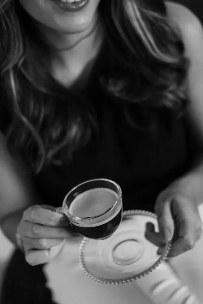 A stylish woman in grayscale holding a cup of espresso, showcasing elegance and relaxation.