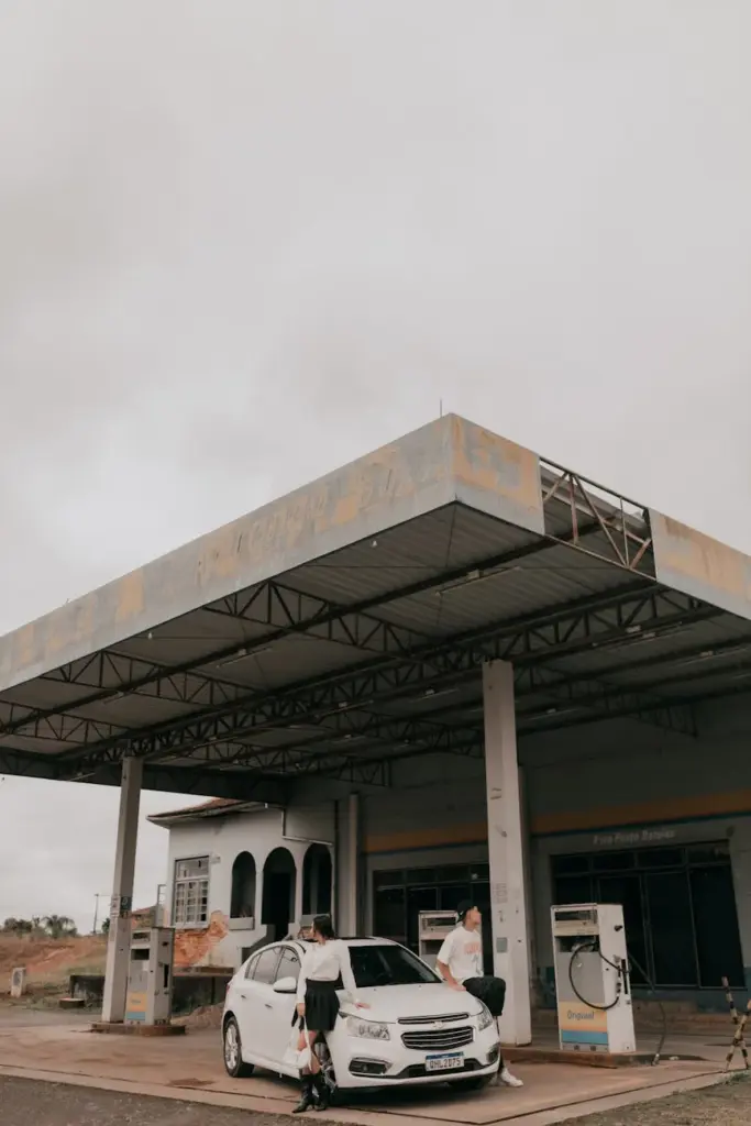 A deserted gas station with a car under a cloudy sky, evoking a moody atmosphere.