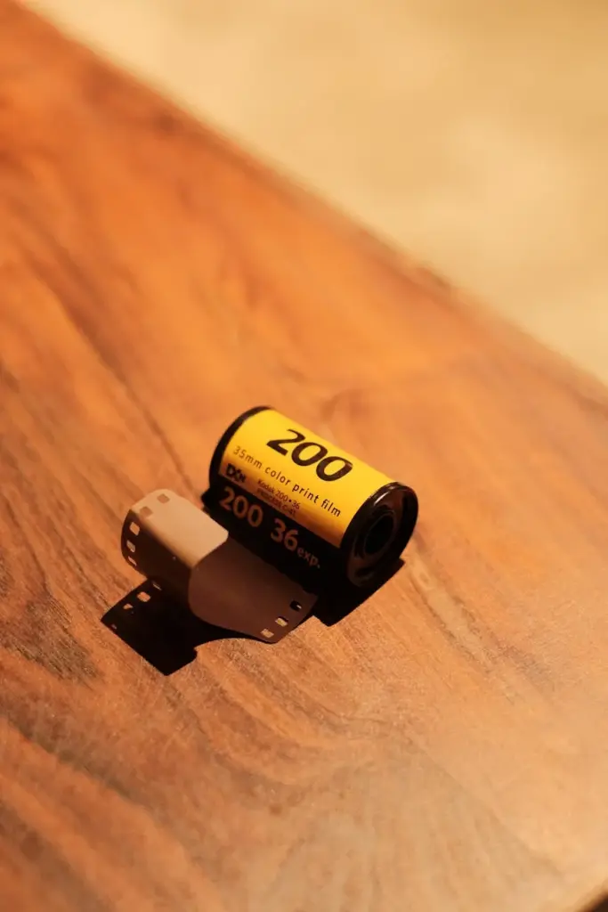 Close-up of a 35mm color film roll on a wooden table, evoking nostalgia.