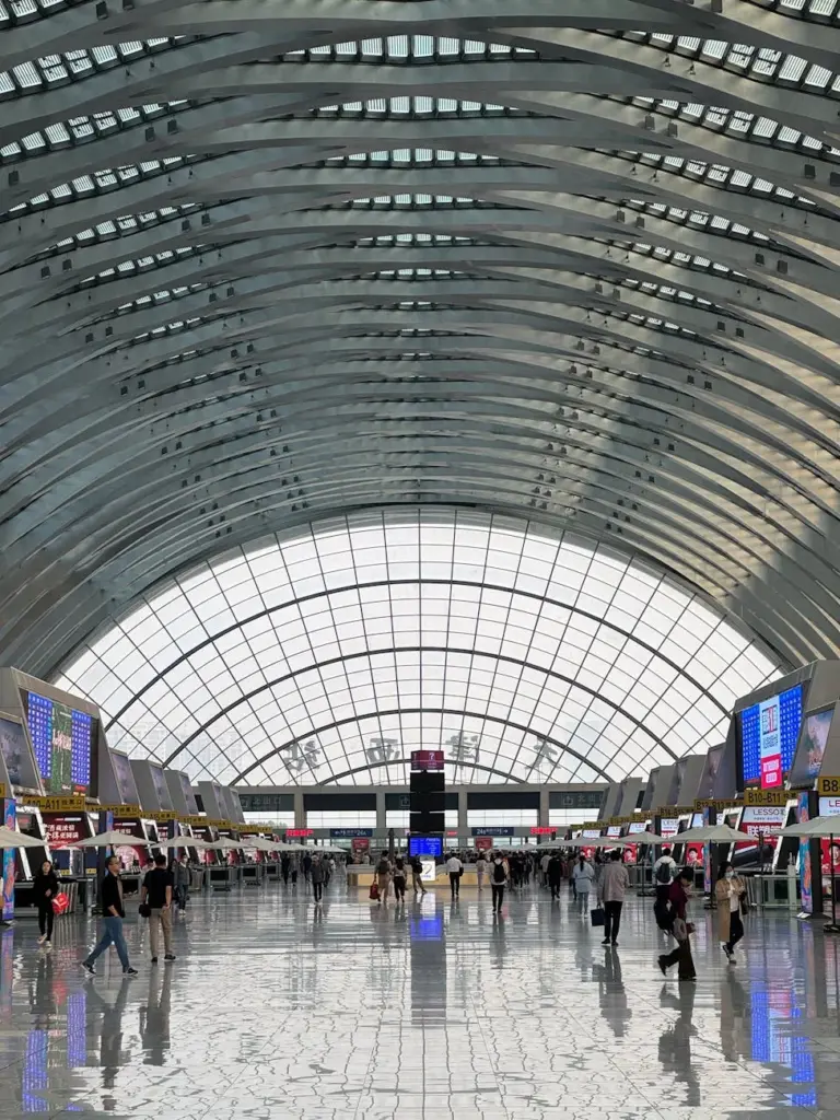 Spacious and futuristic interior of Tianjin Railway Station, bustling with travelers.