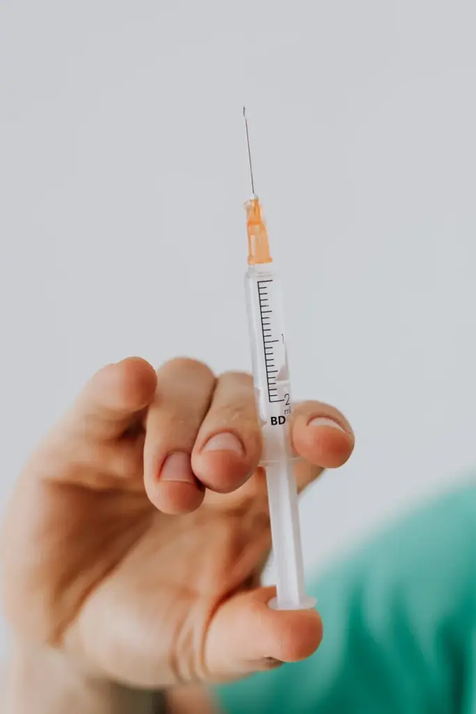 Detailed close-up shot of a hand holding a medical syringe against a neutral background.
