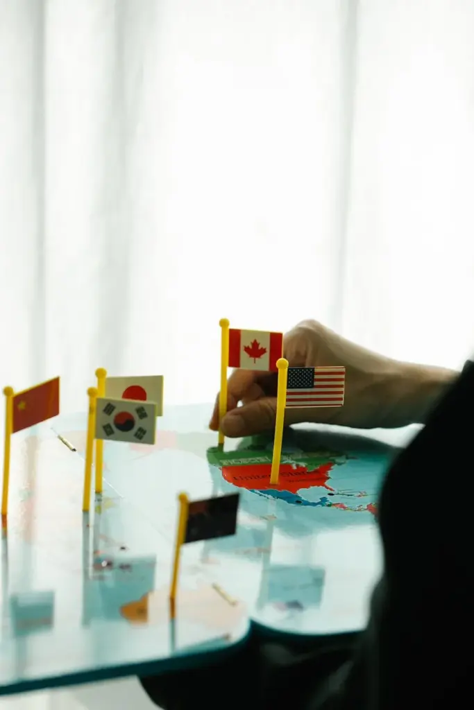 A person places miniature flags on a colorful world map indoors, showcasing global diversity.
