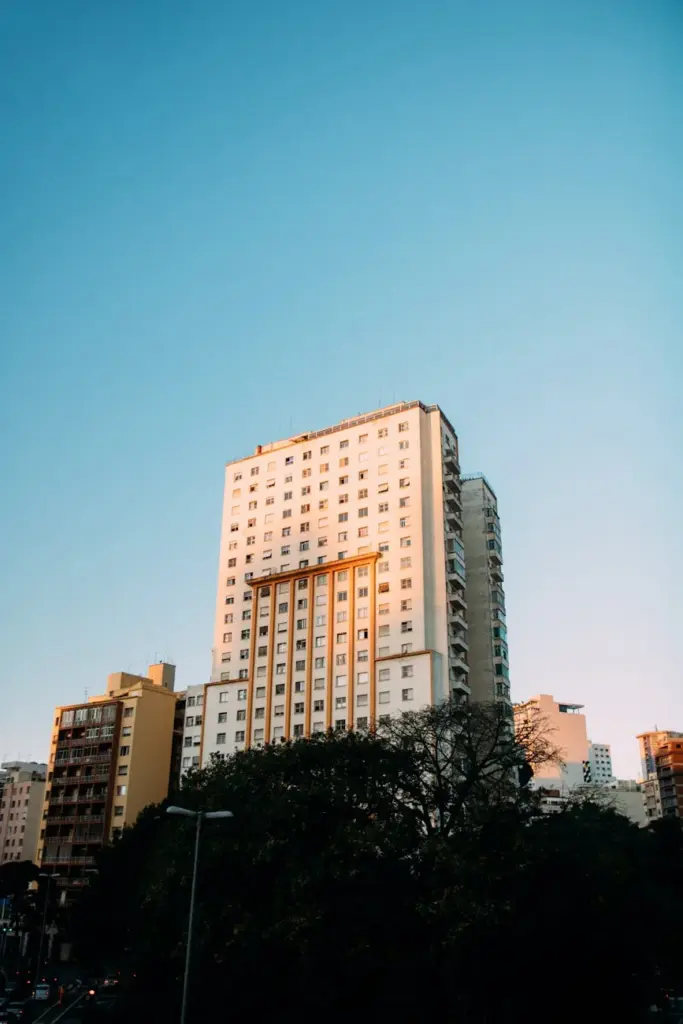 Tall modern building in cityscape under clear blue sky at daytime, showcasing urban architecture.