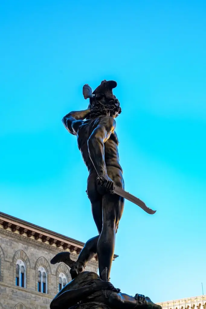 Dramatic view of Renaissance statue in Florence with clear blue sky.