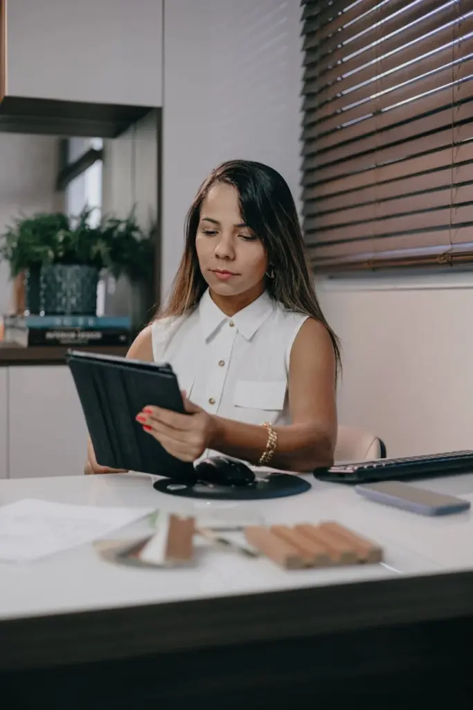 Young woman in an office setting, focused on her tablet work.