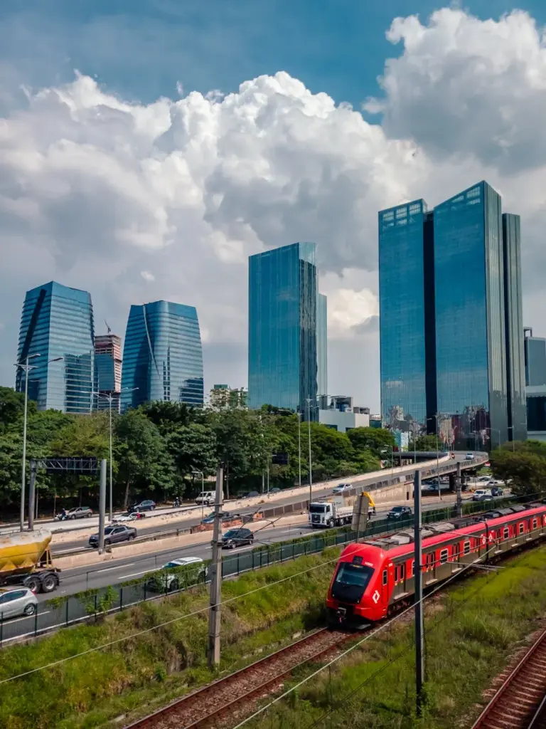 Dynamic cityscape featuring modern skyscrapers and a red train on a sunny day.