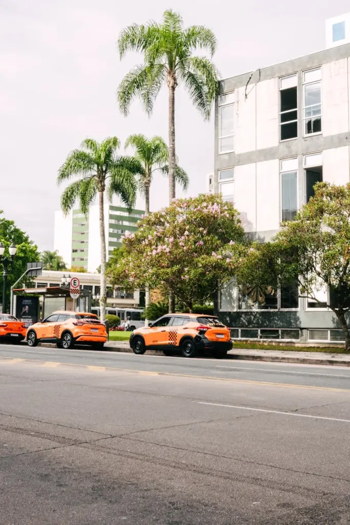 View of urban scene in Curitiba, Brasil, featuring iconic orange taxis and tropical palm trees.