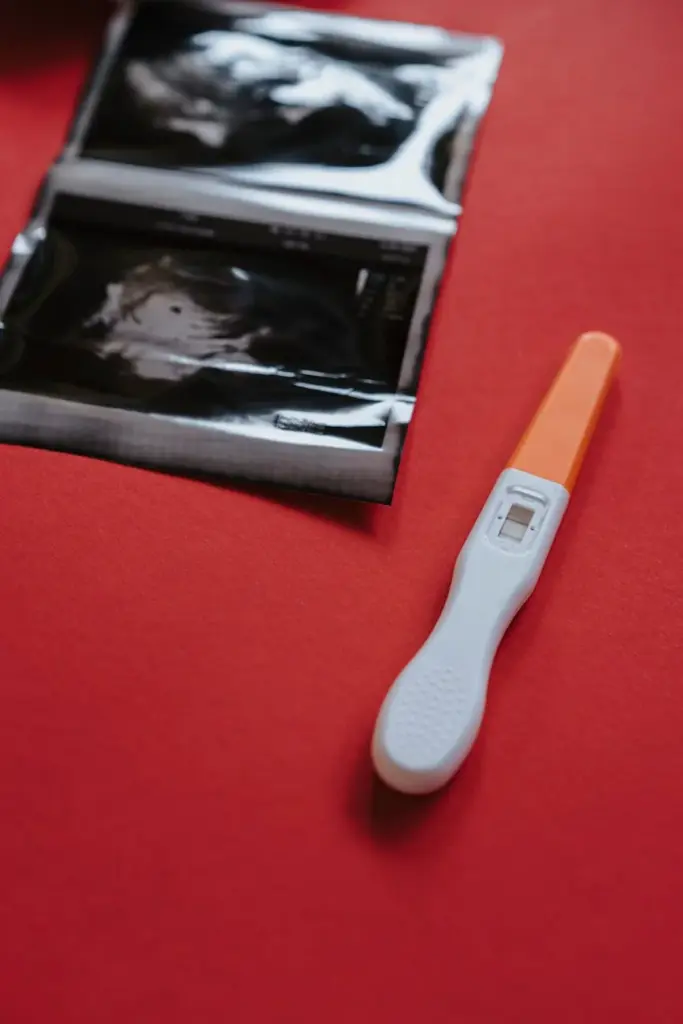 Close-up of a pregnancy test and ultrasound on a red surface, highlighting results.