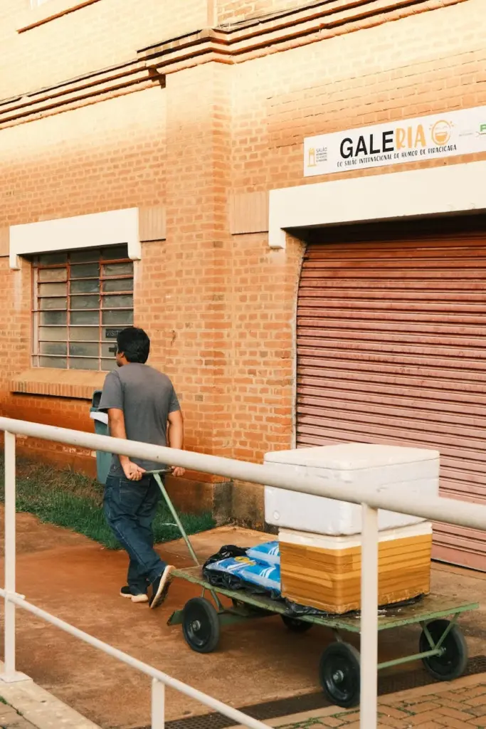 A man pulls a cart beside a brick building in Piracicaba, Brazil. Urban street scene.